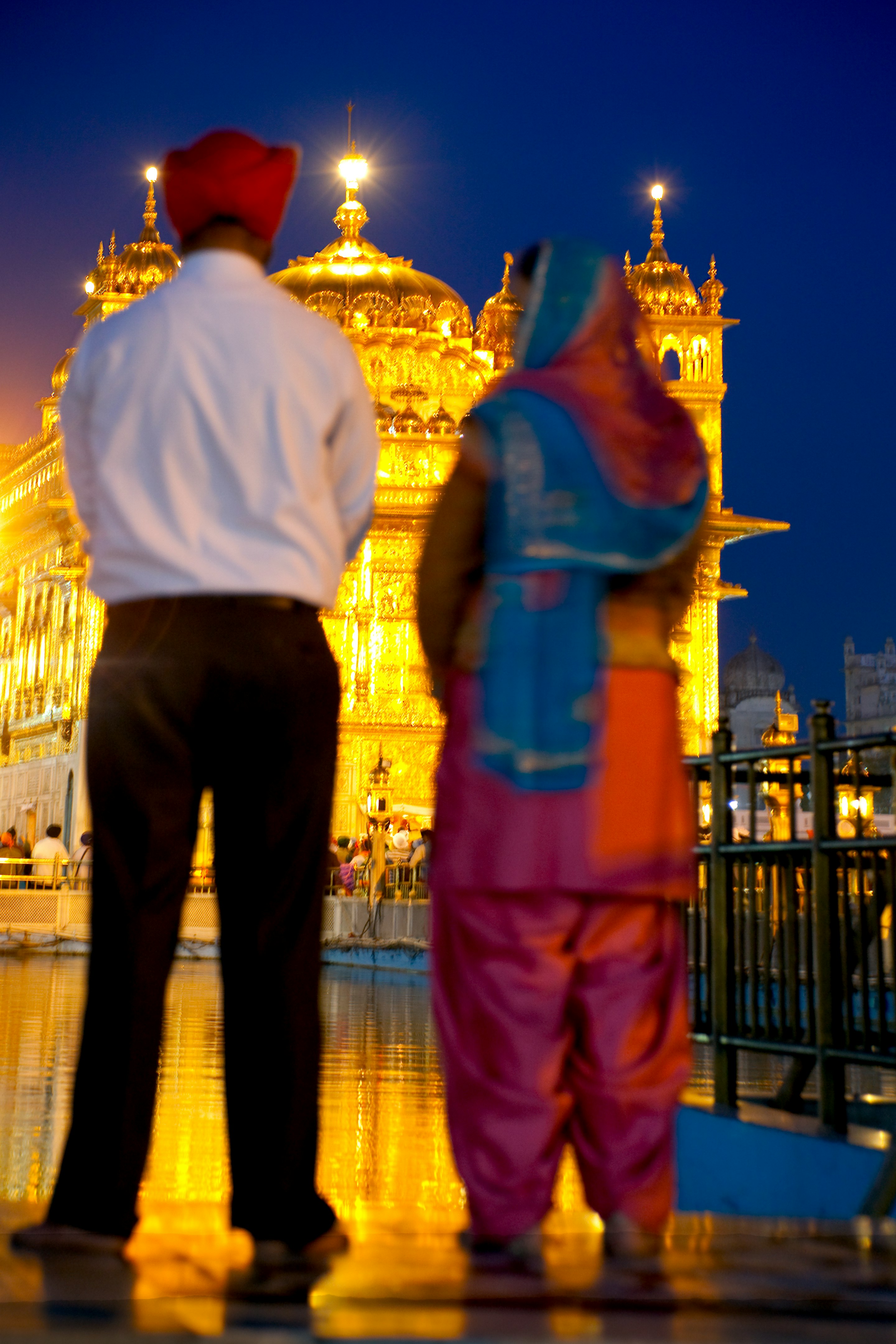 man in white shirt and black pants standing beside woman in blue and brown traditional dress